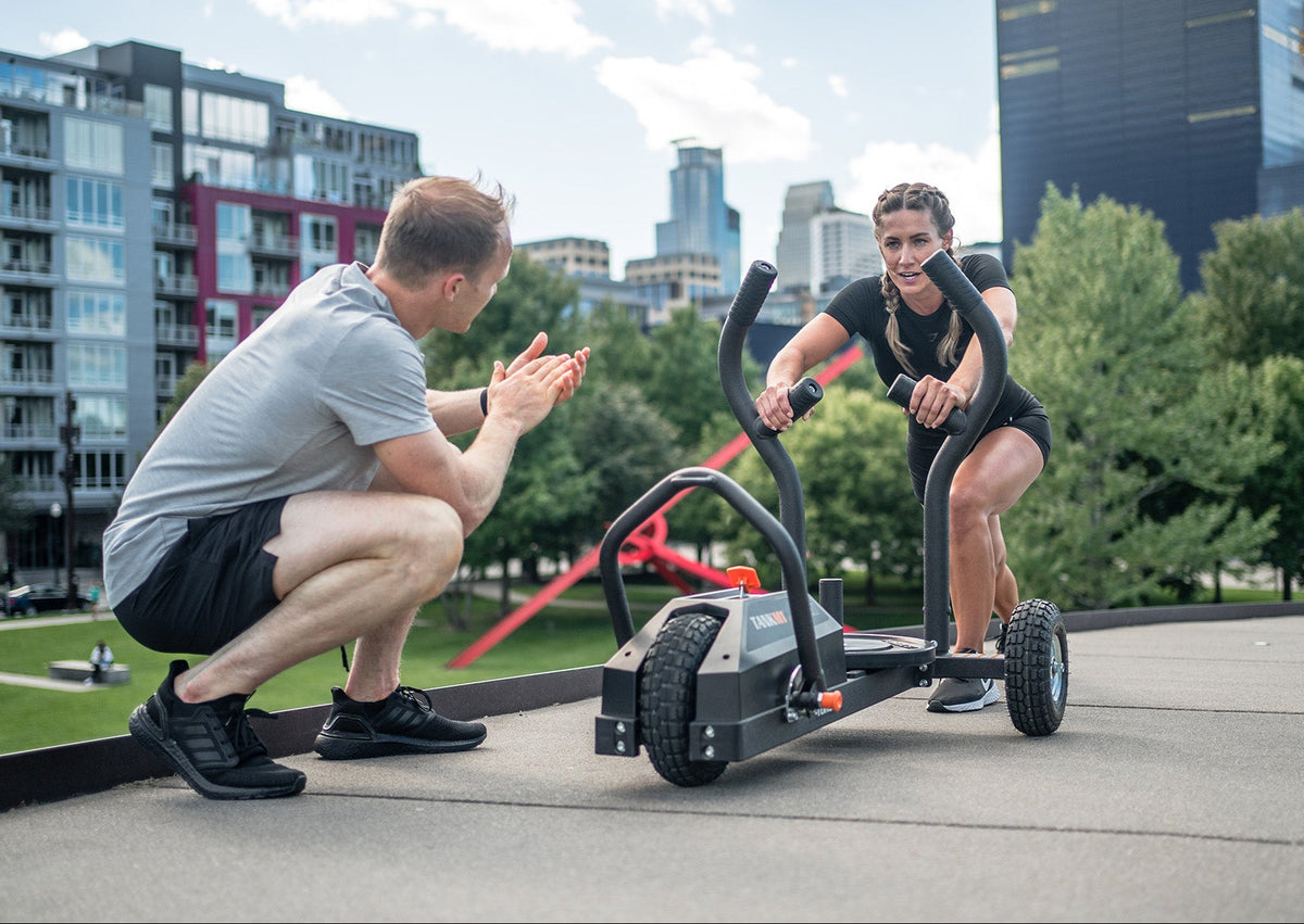 A man and a woman pushing a TANK M1 in a city park