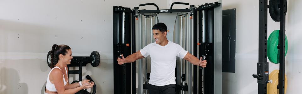 Woman Cheering Man On While He Trains With F9 Fold-Away Functional Trainer In Garage Home Gym