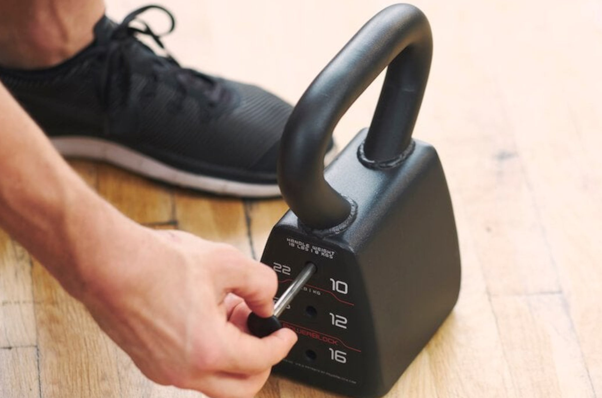 Man Putting Pin Into PowerBlock Standard Adjustable Kettlebell